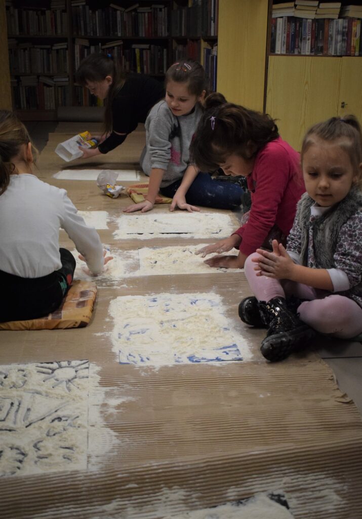 dzieci siedzą na podłodze pracując z mąką
