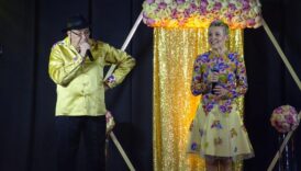 artyści ubrani na złoto mężczyzna i kobieta stoją na złotej scenie