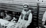 Gminne dożynki na stadionie w Pępowie 15 września 1985 rok ph. ,,Otwórzcie szeroko wrota, bo się zakończyła żniwna robota". ubrana w ludowy strój kobieta siedzi przy stoliku