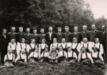 równo ubrani stojący i siedzący ludzie