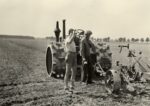 Majątek Krzyżanki przed 1945 rokiem. dwóch pracowników na polu przed maszyną rolniczą, jeden pijący